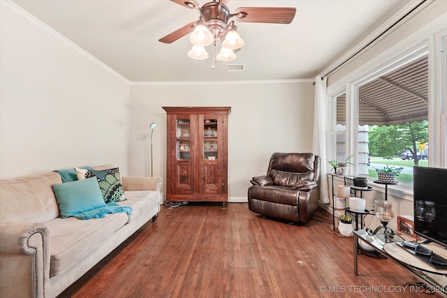 living room featuring dark wood-type flooring, ceiling fan, and ornamental molding