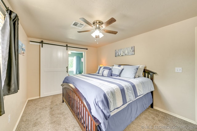 carpeted bedroom with a barn door and ceiling fan