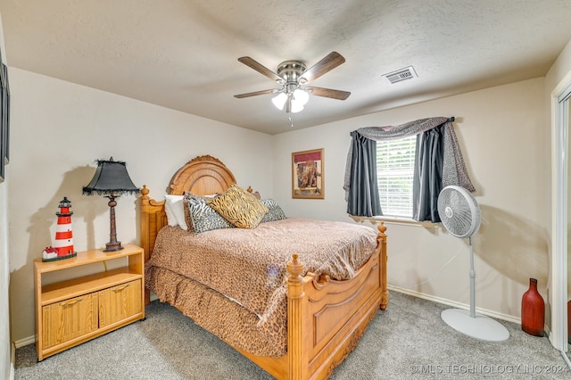 bedroom with a textured ceiling, carpet flooring, and ceiling fan