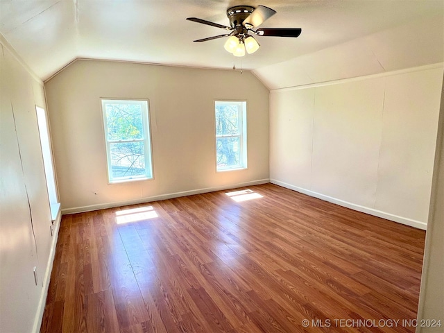 additional living space featuring wood-type flooring, vaulted ceiling, and a healthy amount of sunlight