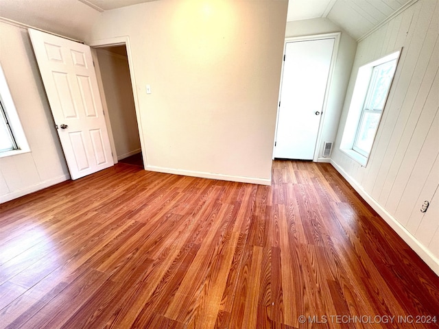 spare room with light hardwood / wood-style flooring, wood walls, and vaulted ceiling