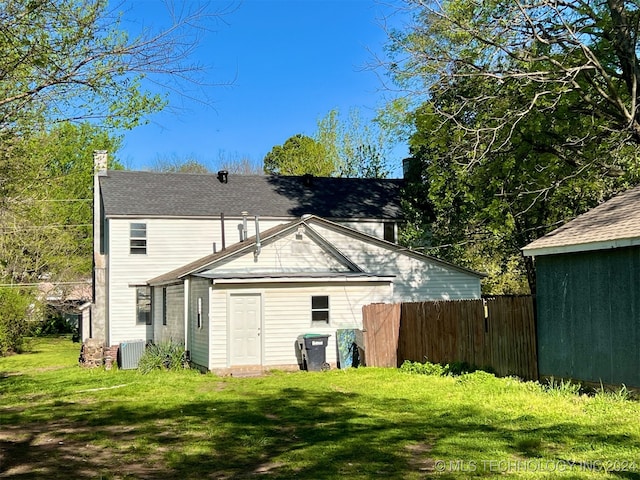 rear view of property featuring cooling unit and a lawn