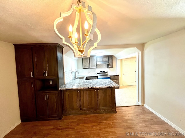 kitchen featuring sink, light stone counters, backsplash, wood-type flooring, and electric range