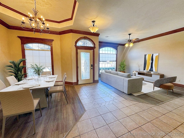 living room featuring ceiling fan with notable chandelier, a textured ceiling, light hardwood / wood-style flooring, and crown molding