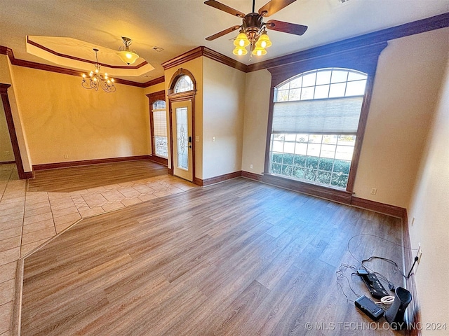 unfurnished room featuring ceiling fan with notable chandelier, a raised ceiling, light hardwood / wood-style flooring, and ornamental molding