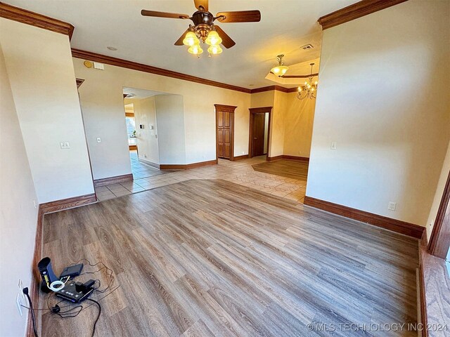 unfurnished room with ceiling fan with notable chandelier, light hardwood / wood-style flooring, and crown molding