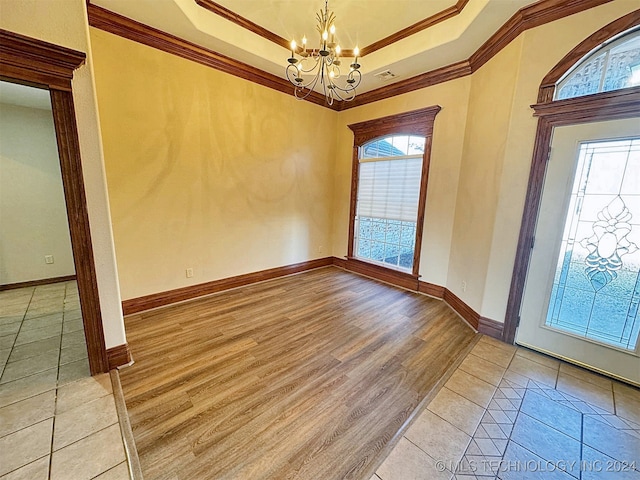 foyer entrance featuring light hardwood / wood-style flooring, a notable chandelier, crown molding, and plenty of natural light