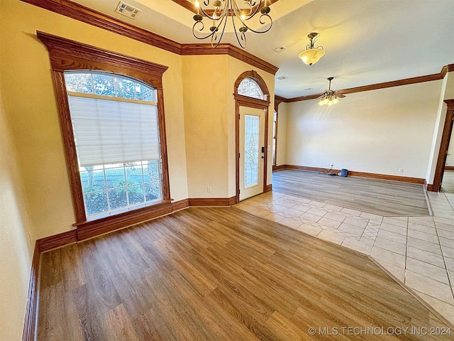 entryway with ceiling fan with notable chandelier, light wood-type flooring, and ornamental molding