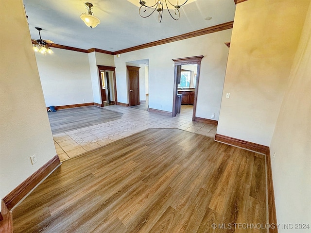 spare room featuring ornamental molding, ceiling fan with notable chandelier, and light hardwood / wood-style floors