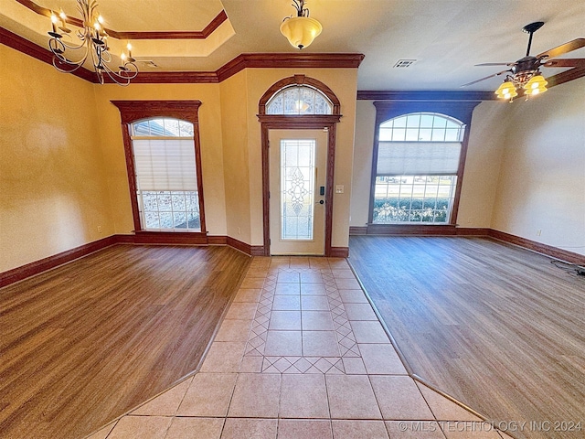 foyer entrance featuring ornamental molding, light wood-type flooring, and ceiling fan with notable chandelier