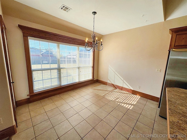 unfurnished dining area featuring a notable chandelier, light tile patterned flooring, and plenty of natural light