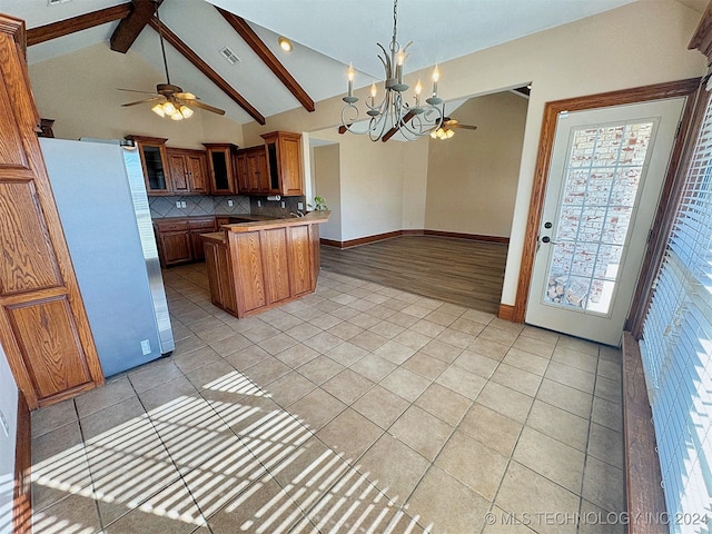 kitchen featuring lofted ceiling with beams, tasteful backsplash, white fridge, light tile patterned floors, and ceiling fan with notable chandelier