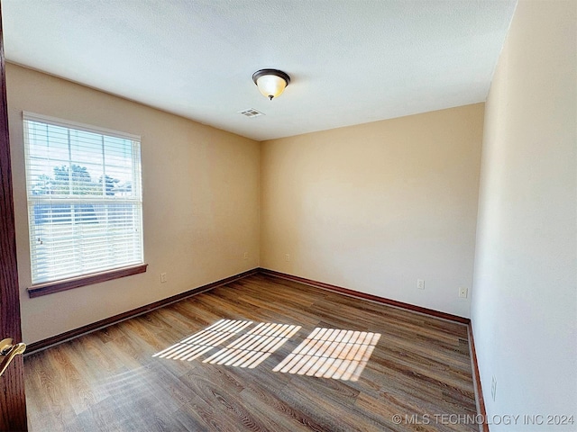 spare room featuring hardwood / wood-style floors and a textured ceiling