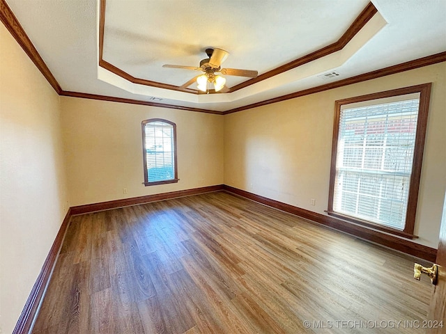 unfurnished room with light hardwood / wood-style floors, ceiling fan, crown molding, and a tray ceiling