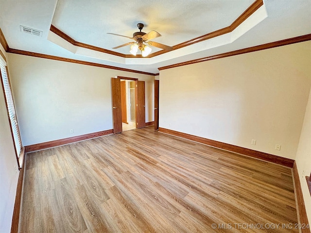 unfurnished bedroom with ceiling fan, a raised ceiling, light hardwood / wood-style floors, and crown molding