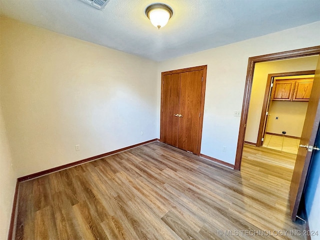 unfurnished bedroom featuring light hardwood / wood-style floors and a closet