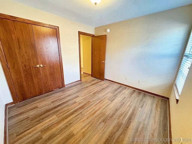 unfurnished bedroom with a closet and light hardwood / wood-style flooring