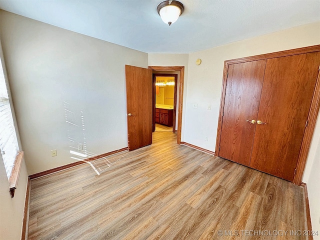 unfurnished bedroom with light hardwood / wood-style flooring and a closet