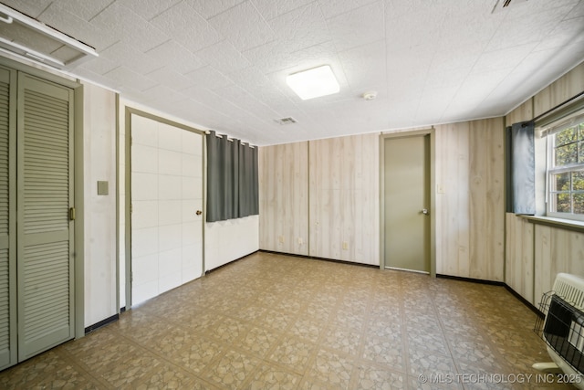 empty room with wood walls and heating unit