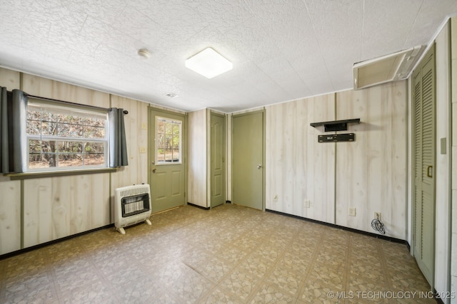 empty room featuring heating unit and wooden walls