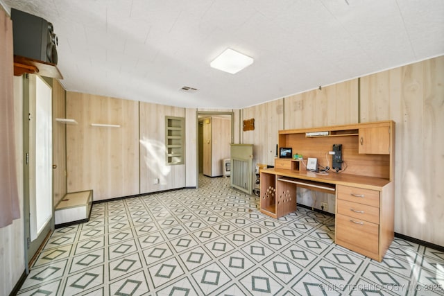 office featuring built in desk and wood walls