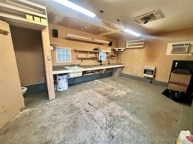 basement with a workshop area, heating unit, a wall unit AC, and sink