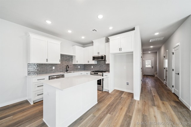 kitchen with a center island, stainless steel appliances, white cabinetry, and sink