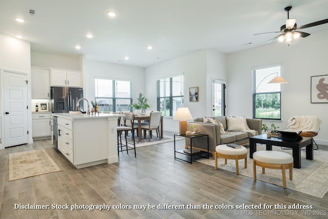 living area with a wealth of natural light, recessed lighting, a ceiling fan, and light wood finished floors