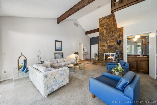 carpeted living room featuring beam ceiling, a textured ceiling, high vaulted ceiling, and a stone fireplace