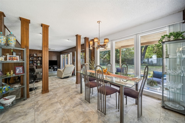 dining room featuring decorative columns, a textured ceiling, and an inviting chandelier