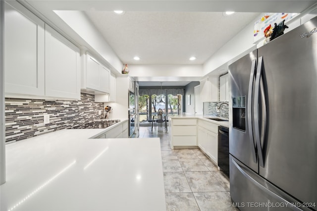 kitchen featuring white cabinets, decorative backsplash, kitchen peninsula, and black appliances