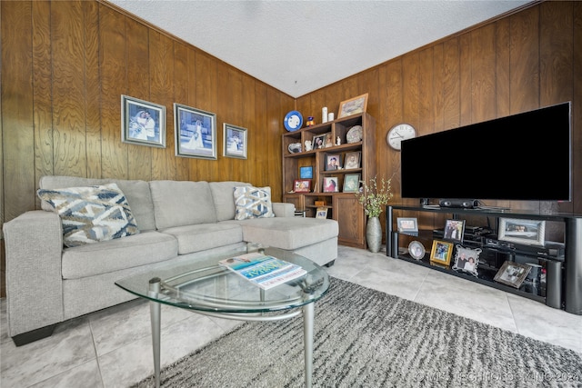 living room featuring light tile patterned floors, a textured ceiling, and wooden walls