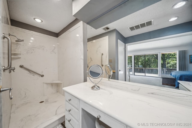 bathroom with vanity, a tile shower, and a textured ceiling