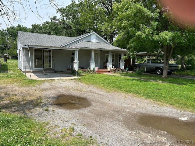 view of front facade featuring a carport, covered porch, and a front yard