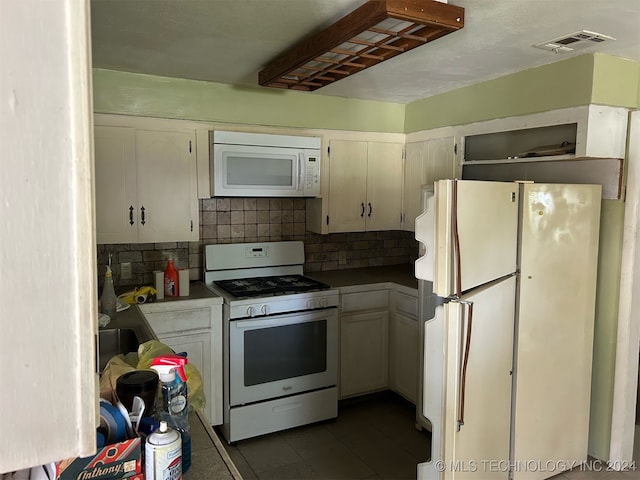 kitchen featuring white cabinets, dark tile patterned flooring, tasteful backsplash, and white appliances