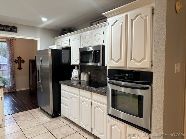 kitchen with stainless steel appliances, white cabinetry, light hardwood / wood-style flooring, and backsplash