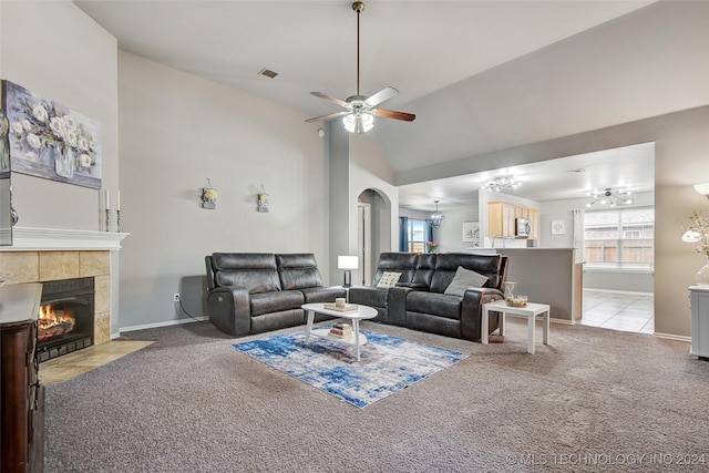 carpeted living room featuring vaulted ceiling, ceiling fan, and a tiled fireplace