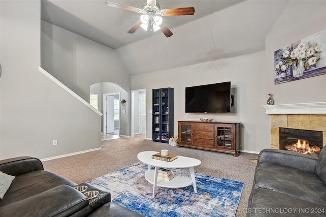 living room featuring ceiling fan, carpet floors, a tile fireplace, and vaulted ceiling