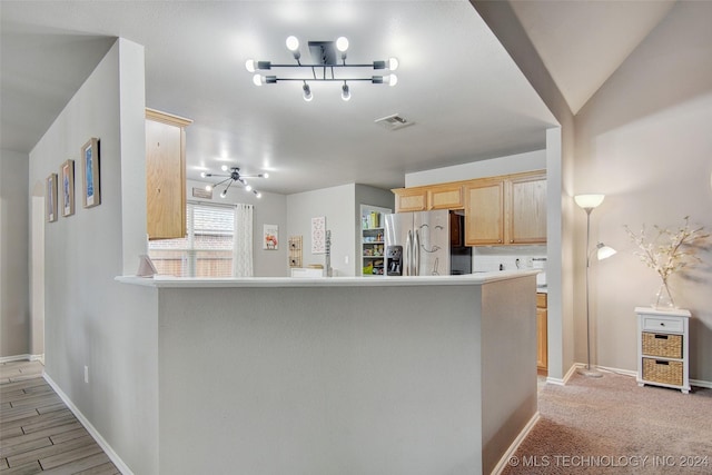 kitchen featuring light brown cabinets, stainless steel fridge, light wood-type flooring, tasteful backsplash, and kitchen peninsula