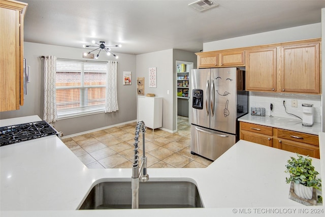 kitchen featuring sink, light tile patterned floors, stainless steel refrigerator with ice dispenser, and an inviting chandelier