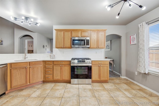 kitchen with sink, tasteful backsplash, a chandelier, light tile patterned floors, and appliances with stainless steel finishes