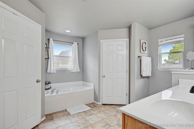 bathroom with tile patterned flooring, vanity, and a washtub