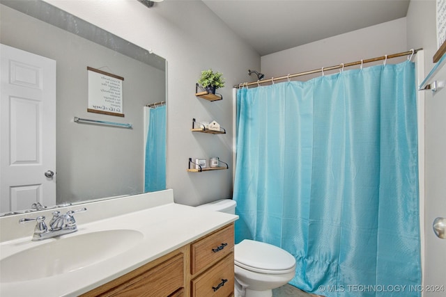 bathroom with curtained shower, vanity, and toilet