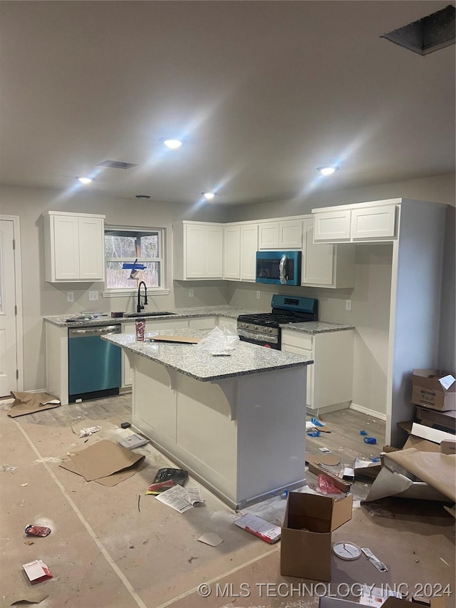 kitchen with sink, stainless steel appliances, light stone countertops, white cabinets, and a kitchen island