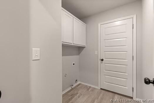 laundry area featuring baseboards, light wood-type flooring, cabinet space, and hookup for an electric dryer