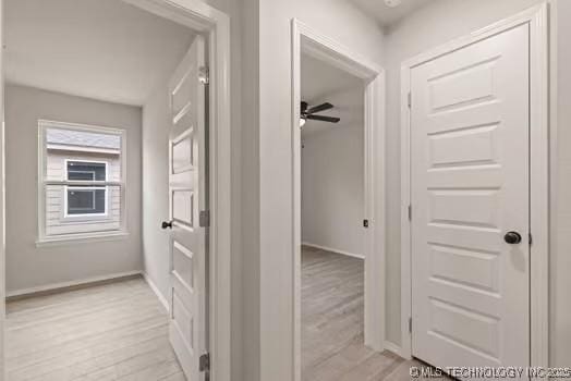 hallway featuring light wood finished floors and baseboards