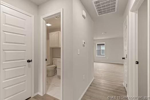 hall featuring wood finished floors, visible vents, and baseboards