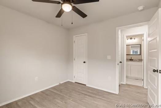 unfurnished bedroom with light wood finished floors, a closet, ensuite bathroom, ceiling fan, and baseboards