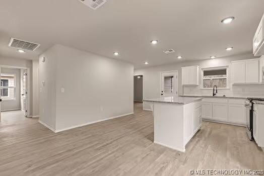 kitchen featuring light wood-style floors, stainless steel range with gas stovetop, visible vents, and a center island