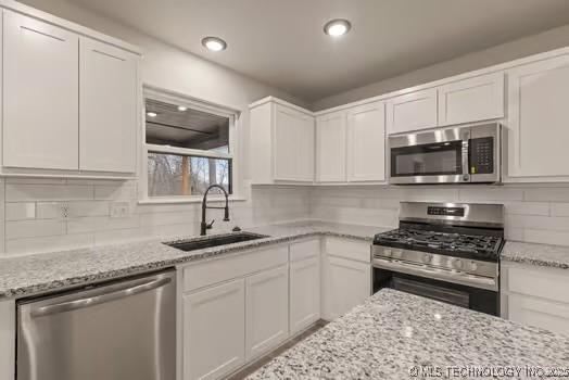 kitchen featuring appliances with stainless steel finishes, a sink, and white cabinets